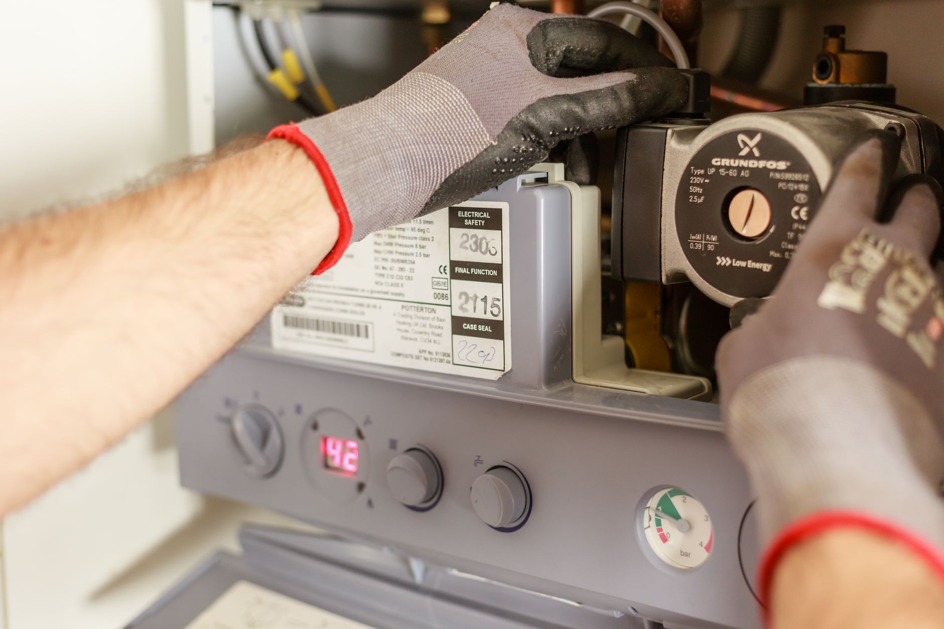 Hands adjusting a valve on a boiler system with a pressure gauge