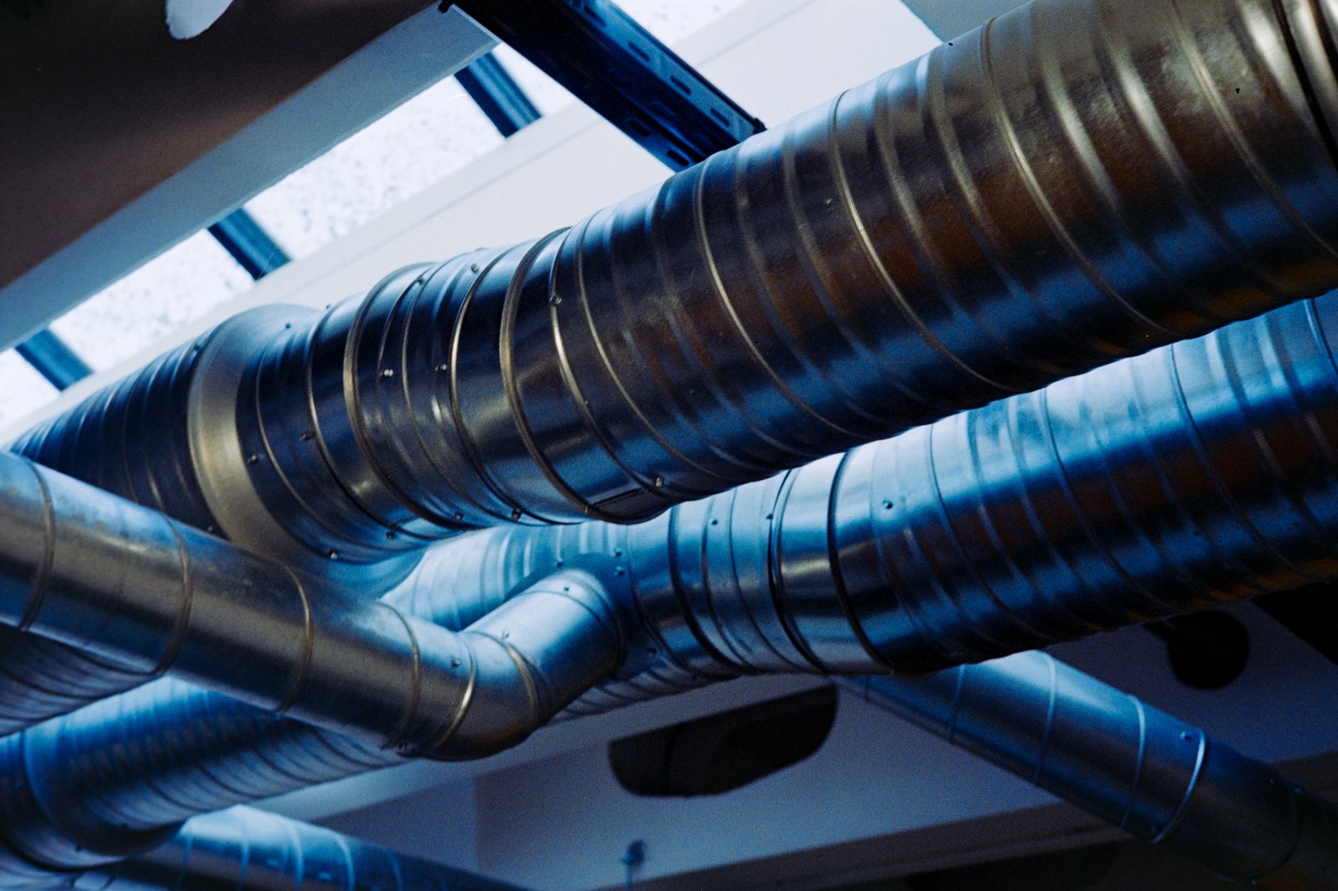 Metal ventilation ducts running along the ceiling of a commercial building